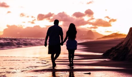 two people walking on a beach - photo by Edgar Chaparro Holiday Romance